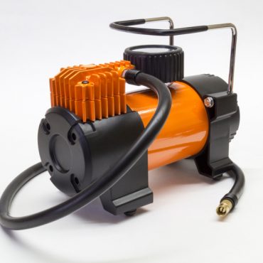 Orange electric compressor for car on light background