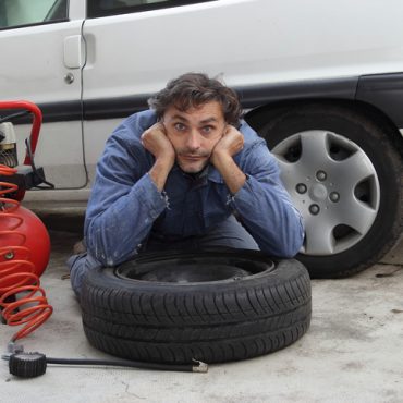 Changing a tire, pensive man and spare wheel